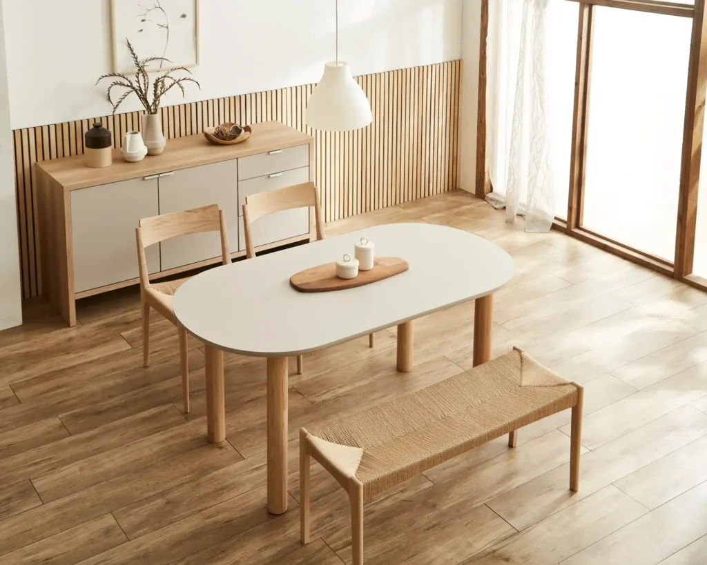 白い天板と天然木の脚を持つ楕円形ダイニングテーブルと天然木チェアが配置されたダイニングルーム。テーブルの高さと椅子の座面高の差(差尺)を測定するための参考画像。