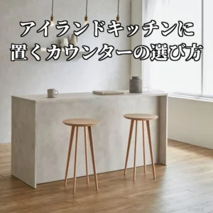 壁から離して置いた幅178cmのアイランドキッチンカウンター。収納のないフラットな面を手前にして、木のスツールが2脚並んでいる